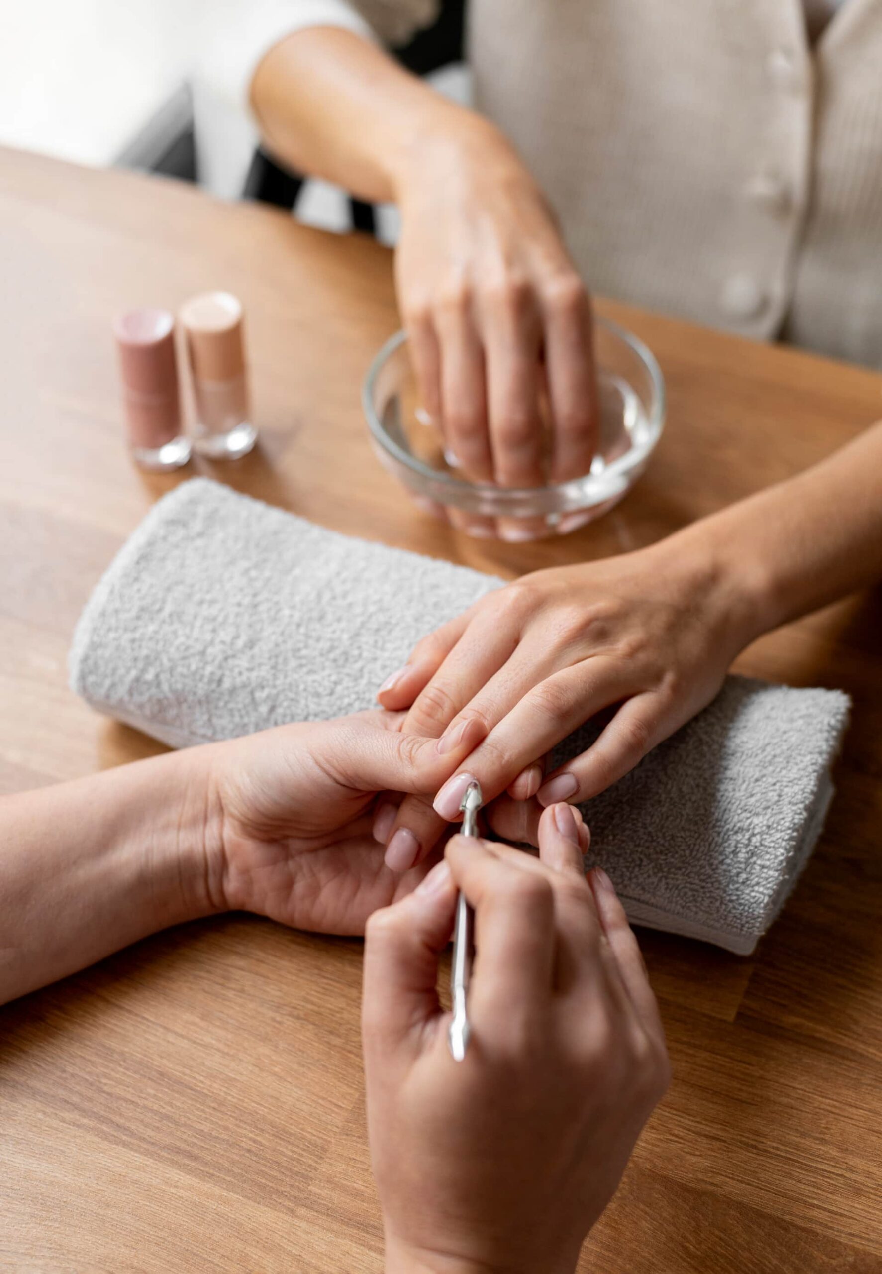 manicurist doing a manicure on client's fingernails